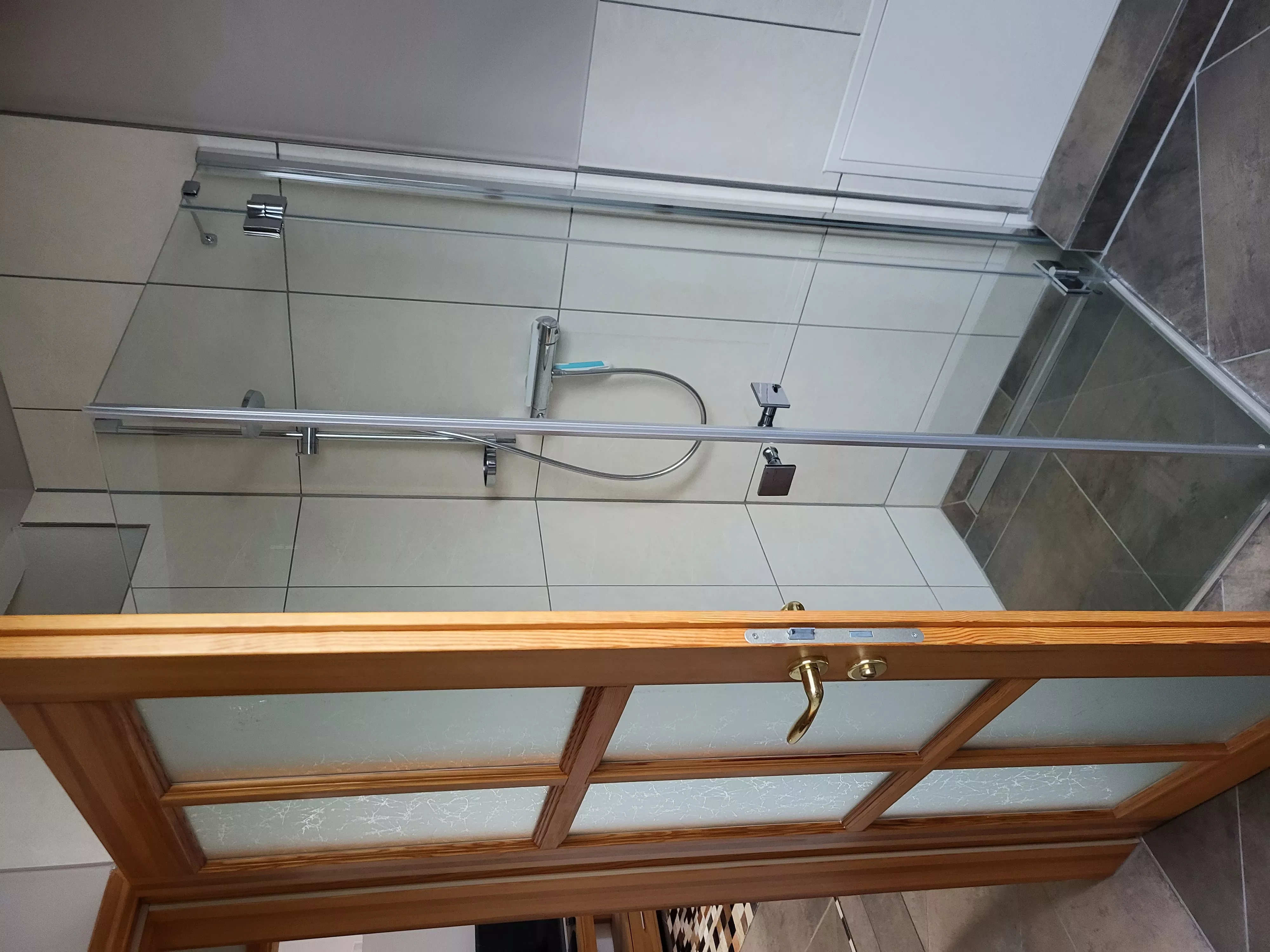 Modernes Badezimmer des Lofts in der Stadtvilla ValenTina in Waren an der Müritz mit ebenerdiger Glasdusche und heller, freundlicher Fliesengestaltung