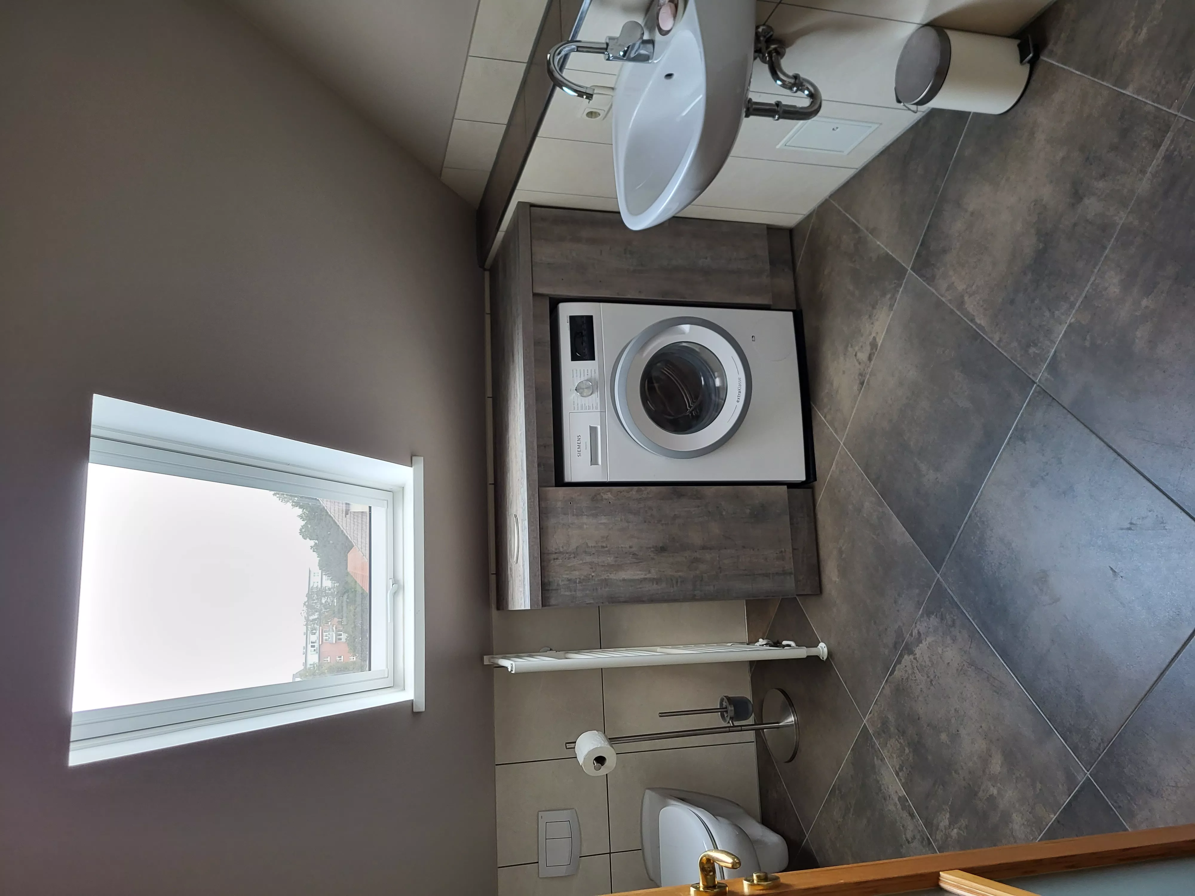 Zweite Badansicht des Loft-Ferienapartments in Waren an der Müritz mit Waschbecken, WC und integrierter Waschmaschine für den Aufenthalt