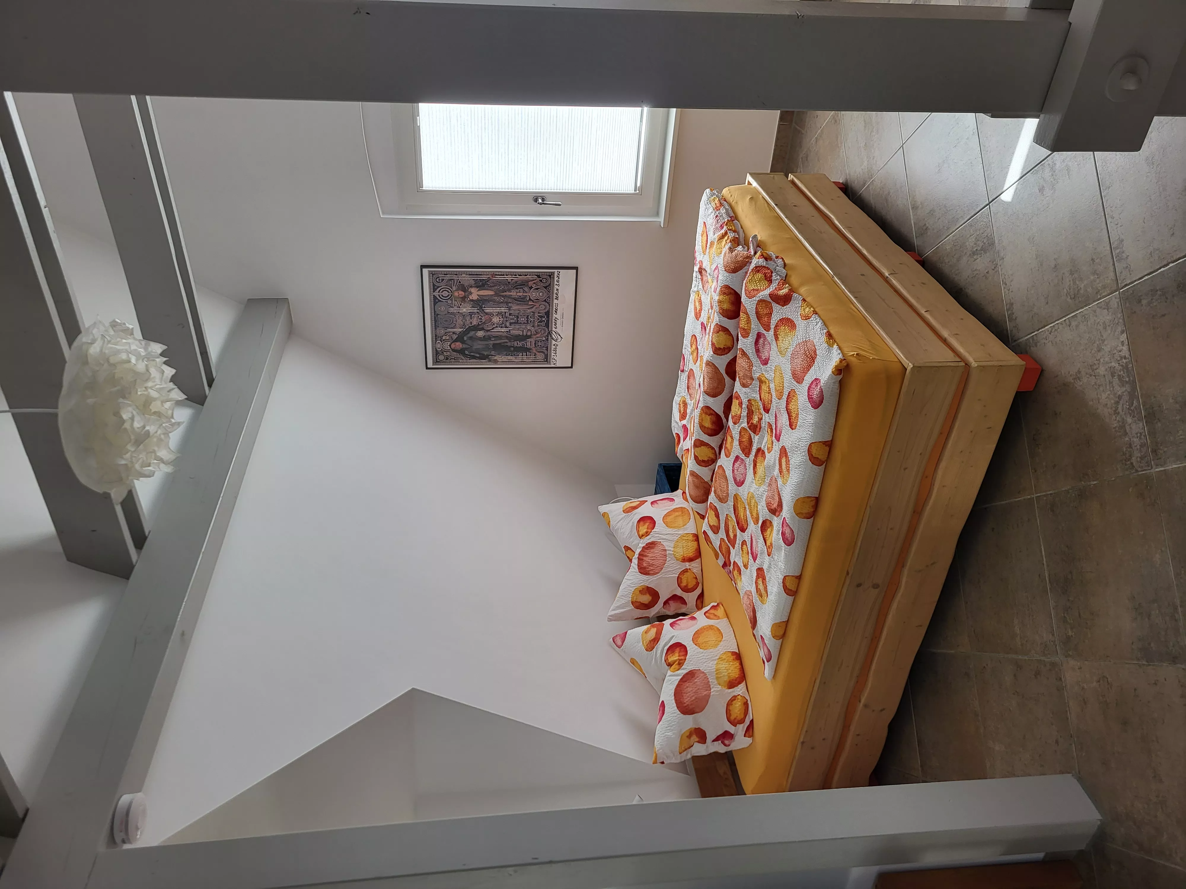 Zweites Schlafzimmer des Loft-Ferienapartments in Waren an der Müritz mit Doppelbett und Bettwäsche in warmen Orange- und Terrakottatönen
