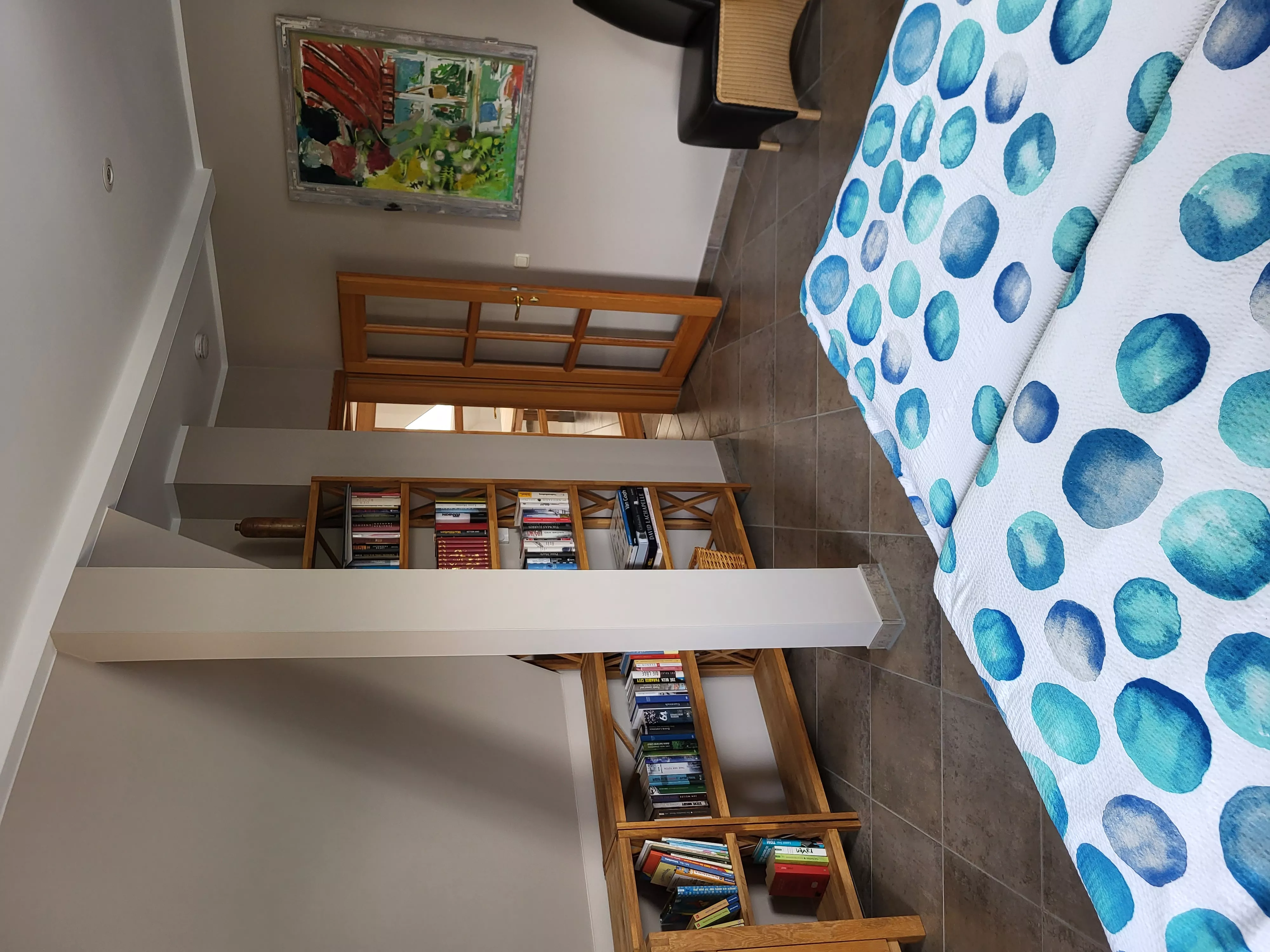 Weitere Ansicht des ersten Schlafzimmers im Loft der Stadtvilla ValenTina mit gefülltem Bücherregal und dekorativem Kunstwerk – Ferienwohnung in Waren an der Müritz