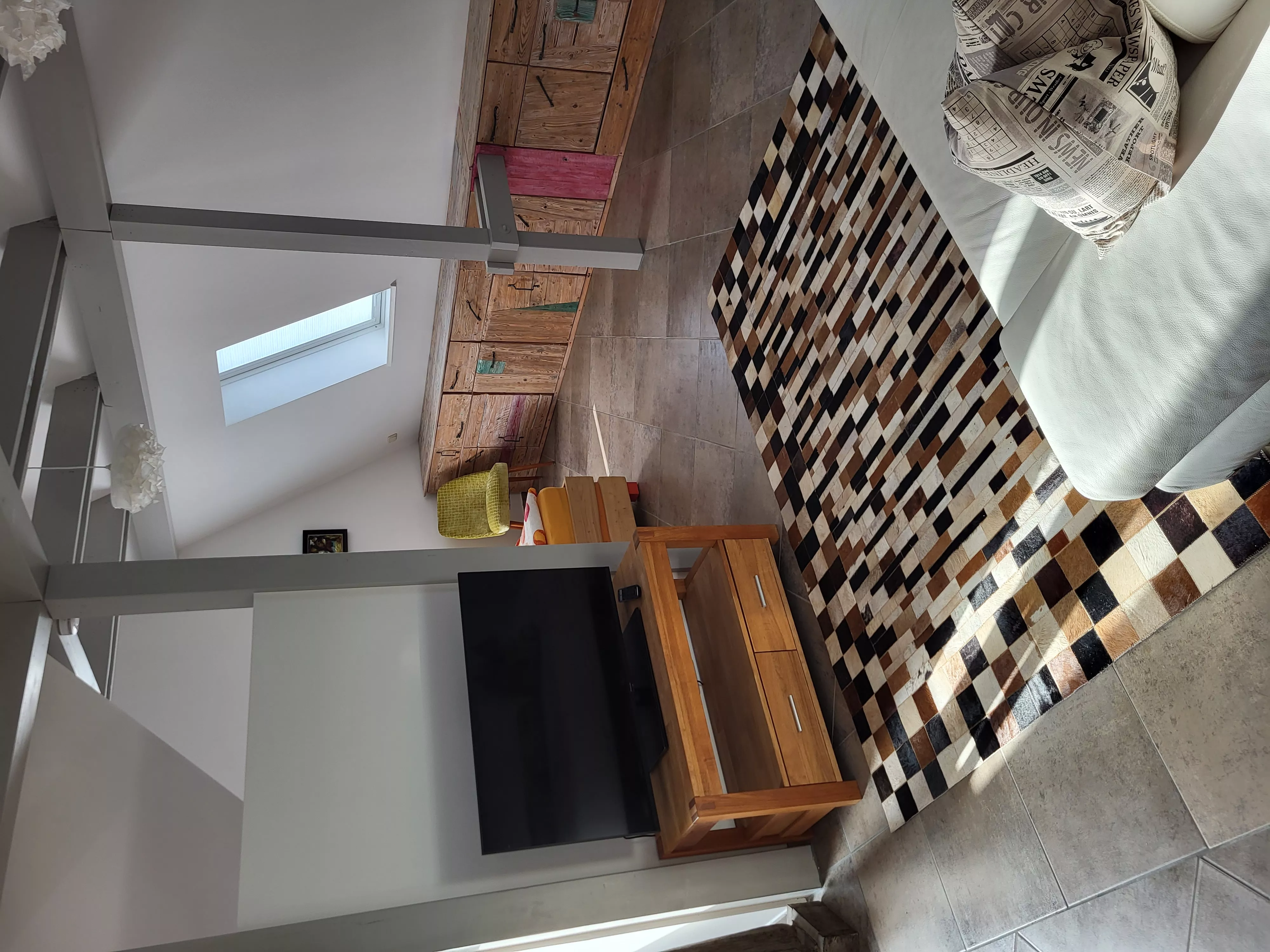 Heller Wohnbereich des Loft-Ferienapartments in der Stadtvilla ValenTina in Waren an der Müritz mit gemütlichem Sofa, moderner Kunst an den Wänden und offener Galerie zur zweiten Ebene